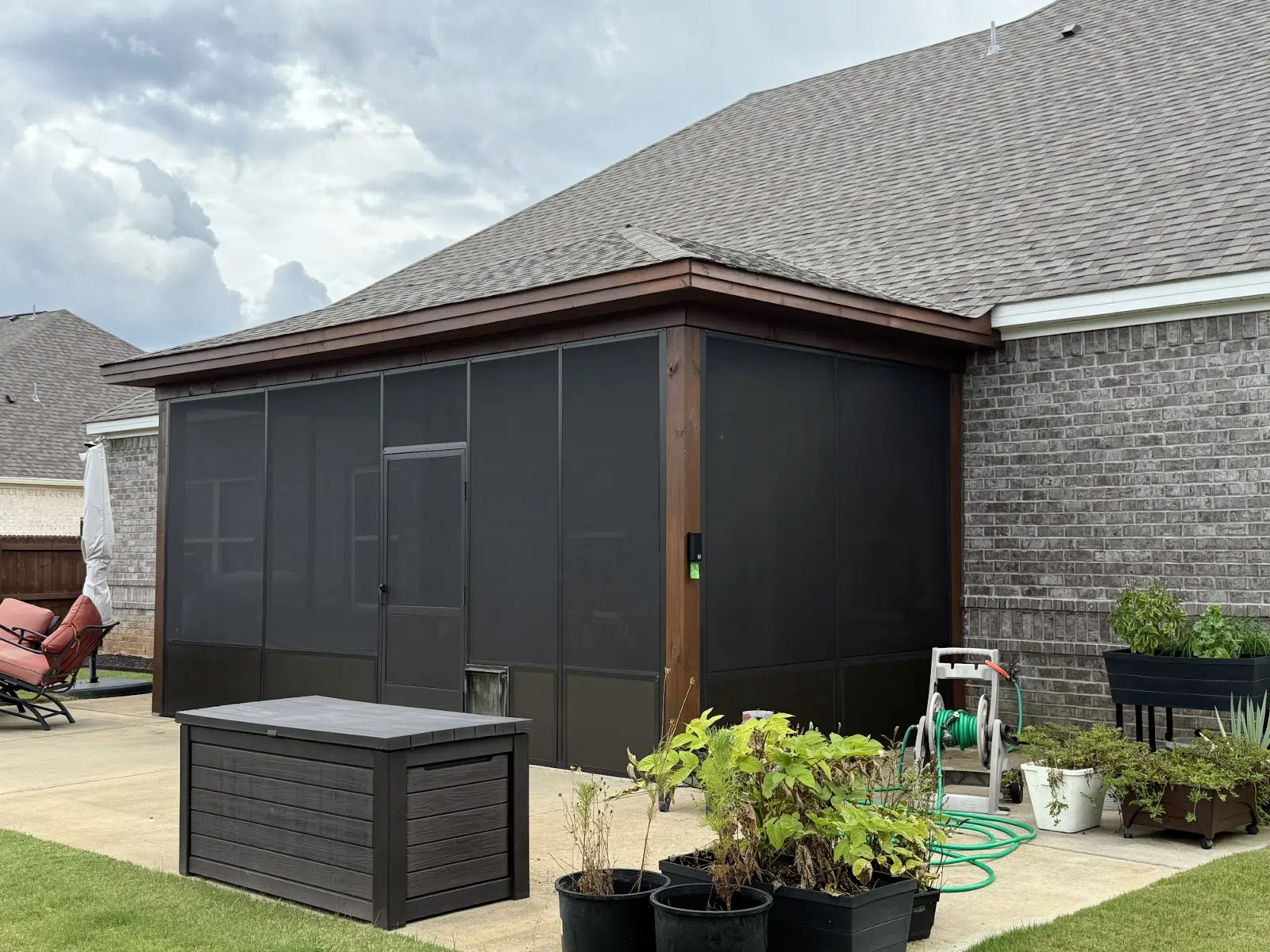 Dark screened porch with wood trim attached to brick home — Three Rivers Aluminum Awnings, LLC. in Dothan