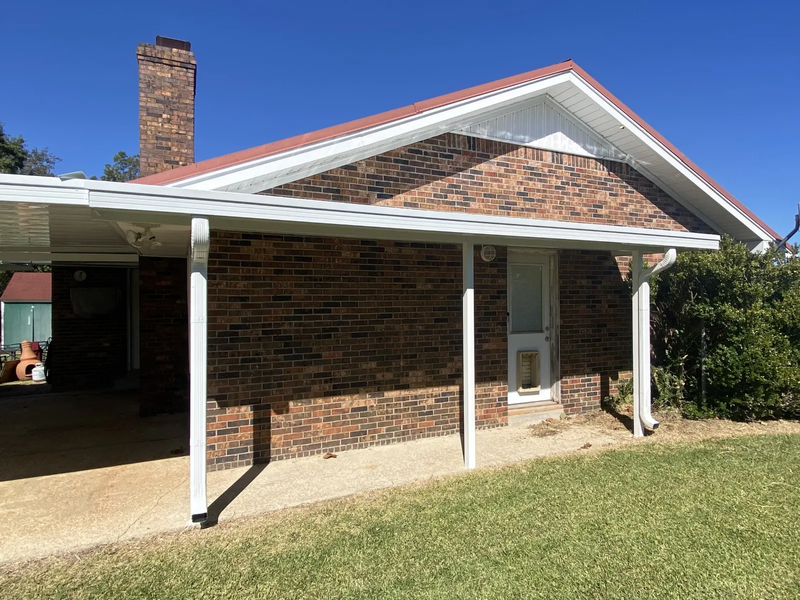 White aluminum cover running along the side of a brick house