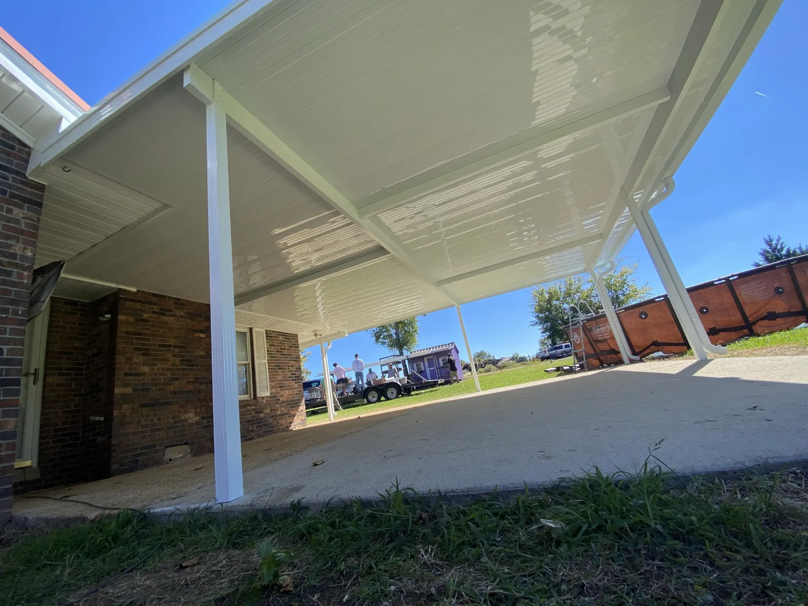 Underside of a white aluminum patio cover with its support posts and beams