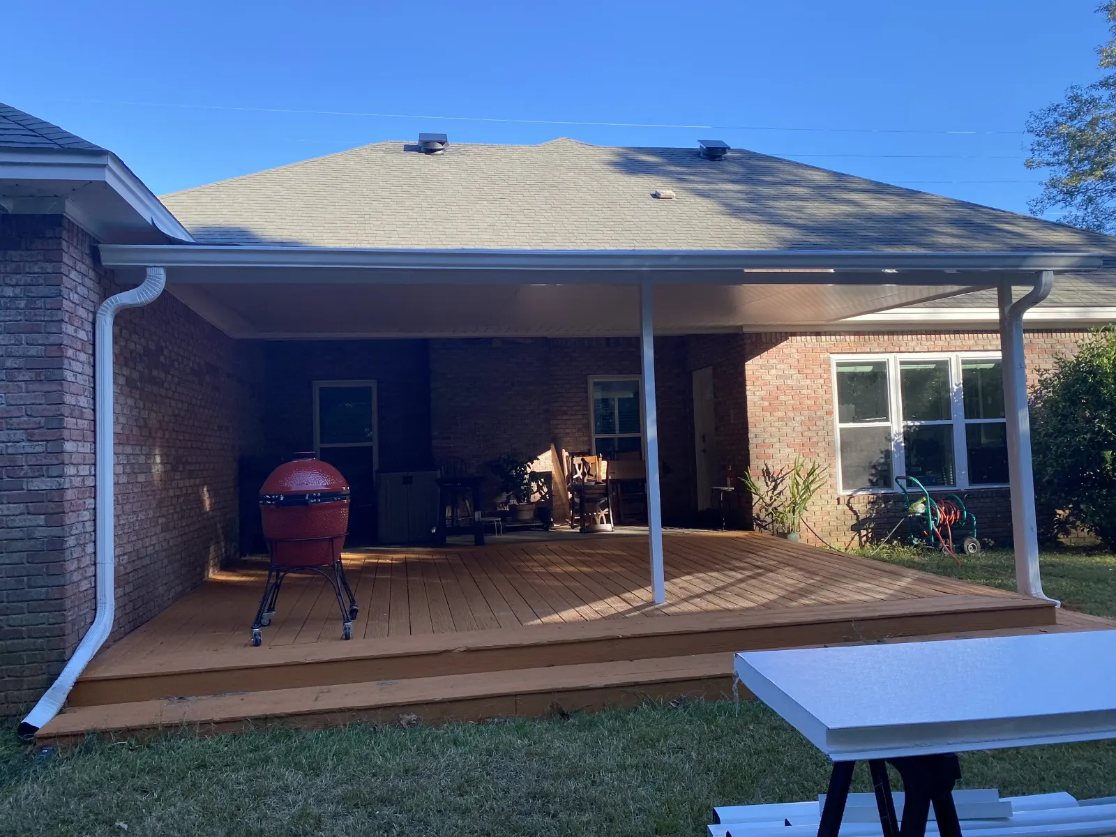 White aluminum patio cover with seamless gutters and downspouts over a backyard deck